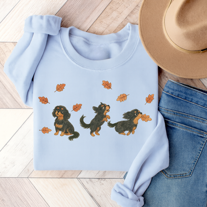 Black Tan Cavalier Chasing Leaves Sweatshirt Light Blue